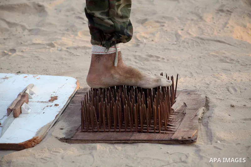 A Palestinian trainer stands on tapered nails during training in a summer camp organized by Hamas movement at Shati refugee camp in Gaza City July 10, 2012. Hamas movement organized dozens of summer camps for Palestinian...