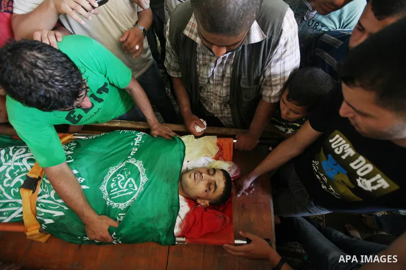 Palestinians mourn over the body of Hamas militant Mahmud Al-Heggi during his funeral in the Al Zaitun area in the east of Gaza city, 12 July 2012. Al Heggi was killed and others wounded after an Israeli air strike in AL...