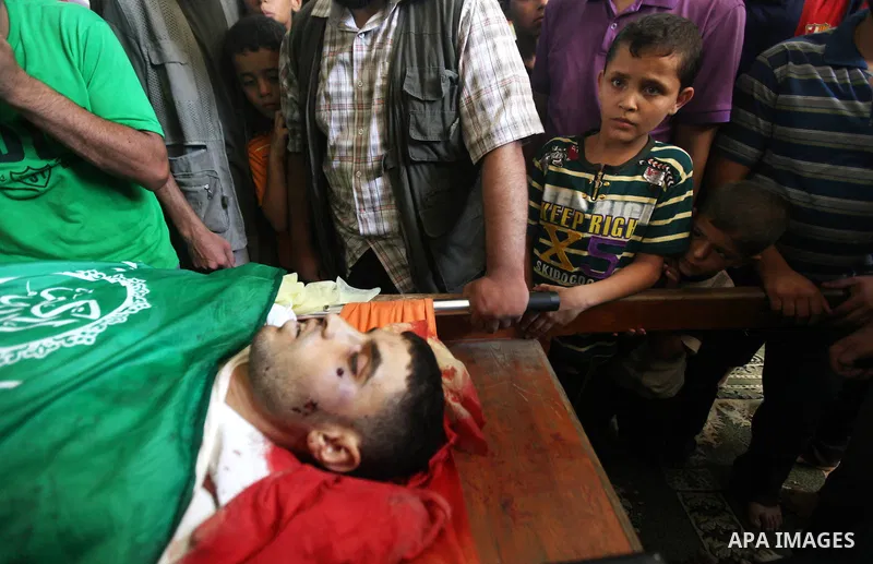 Palestinians mourn over the body of Hamas militant Mahmud Al-Heggi during his funeral in the Al Zaitun area in the east of Gaza city, 12 July 2012. Al Heggi was killed and others wounded after an Israeli air strike in AL...