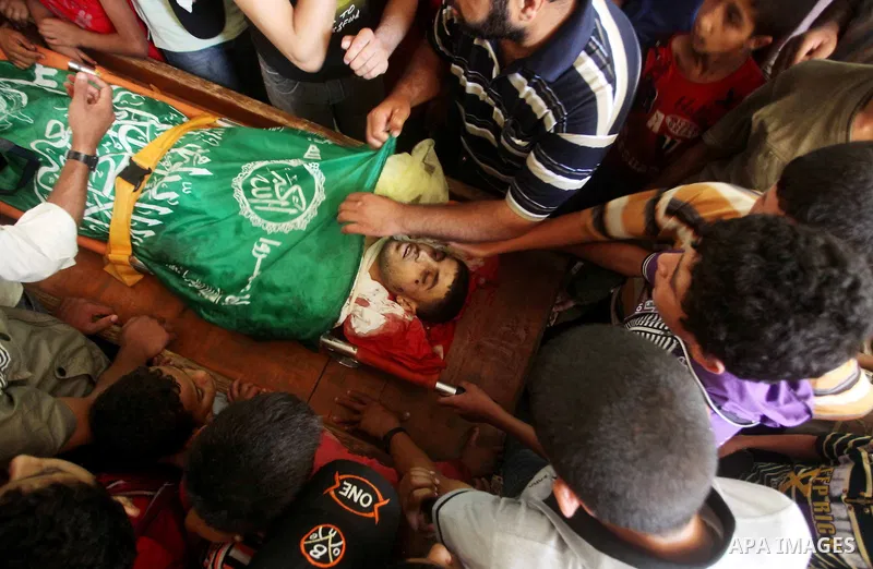 Palestinians mourn over the body of Hamas militant Mahmud Al-Heggi during his funeral in the Al Zaitun area in the east of Gaza city, 12 July 2012. Al Heggi was killed and others wounded after an Israeli air strike in AL...