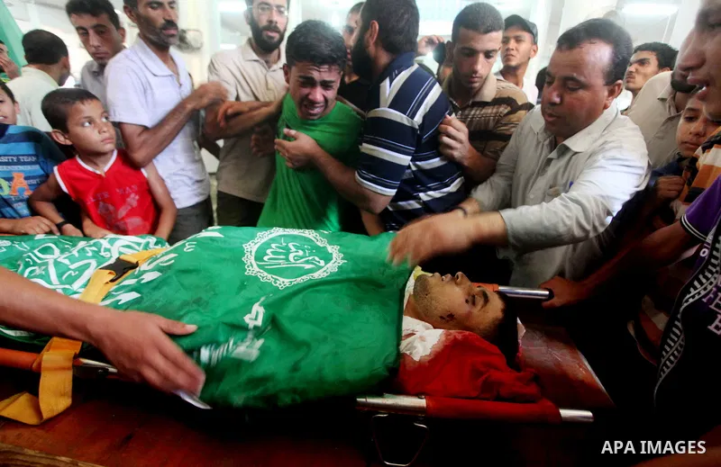 Palestinians mourn over the body of Hamas militant Mahmud Al-Heggi during his funeral in the Al Zaitun area in the east of Gaza city, 12 July 2012. Al Heggi was killed and others wounded after an Israeli air strike in AL...