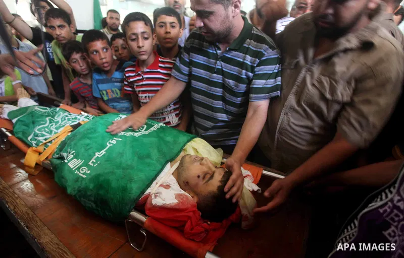 Palestinians mourn over the body of Hamas militant Mahmud Al-Heggi during his funeral in the Al Zaitun area in the east of Gaza city, 12 July 2012. Al Heggi was killed and others wounded after an Israeli air strike in AL...