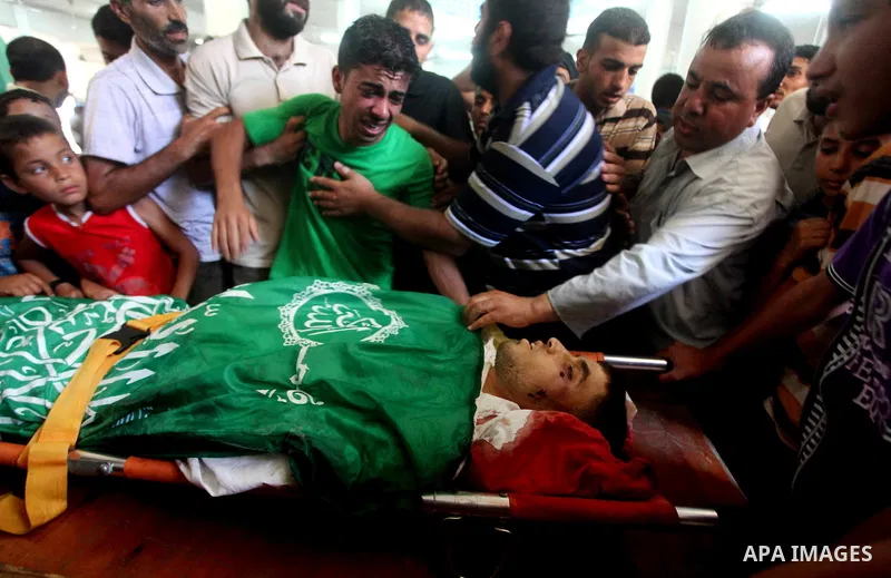 Palestinians mourn over the body of Hamas militant Mahmud Al-Heggi during his funeral in the Al Zaitun area in the east of Gaza city, 12 July 2012. Al Heggi was killed and others wounded after an Israeli air strike in AL...