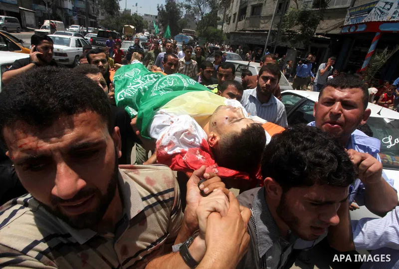 Palestinian mourners carry the body of Hamas militant Mahmud Al-Heggi during his funeral in the Al Zaitun area in the east of Gaza city, 12 July 2012. Al Heggi was killed and others wounded after an Israeli air strike in...