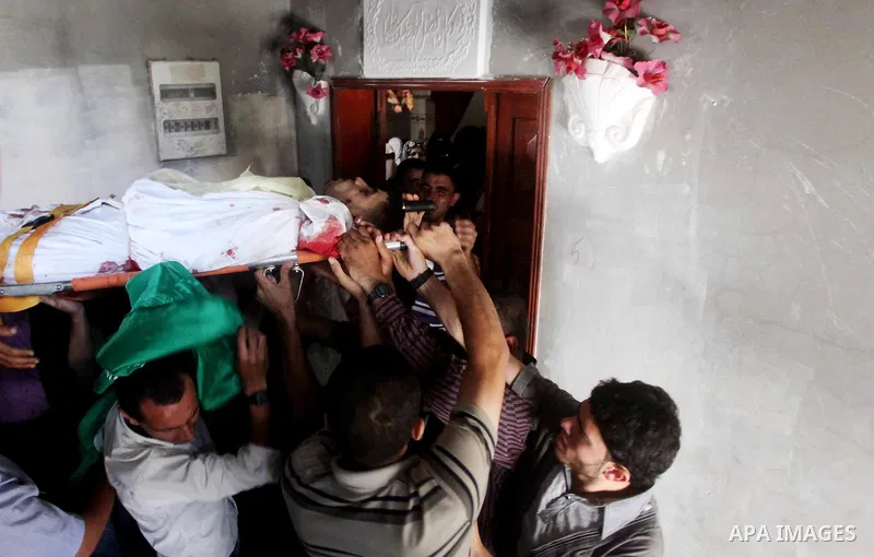 Palestinian mourners carry the body of Hamas militant Mahmud Al-Heggi during his funeral in the Al Zaitun area in the east of Gaza city, 12 July 2012. Al Heggi was killed and others wounded after an Israeli air strike in...