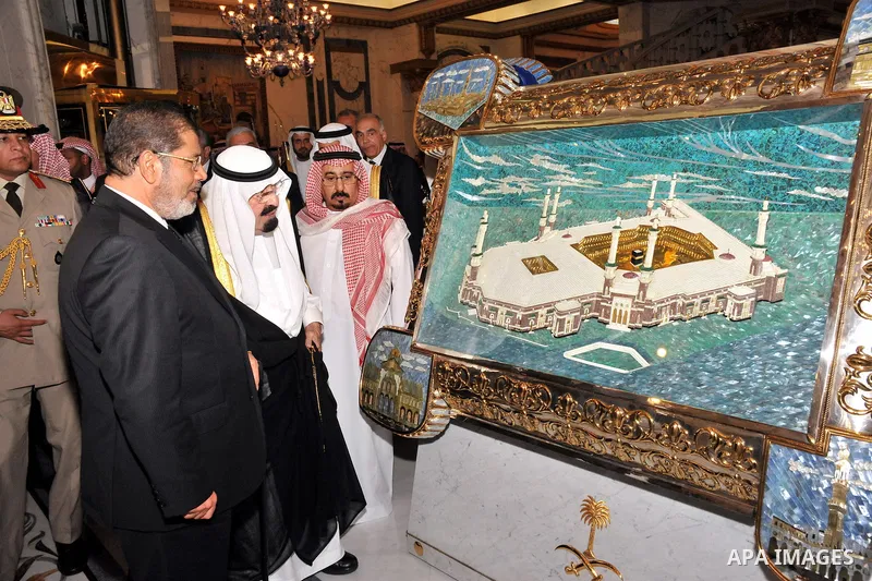 Saudi Arabia King Abdullah (R) and Egyptian President Mohamed Morsi looking at a painting of the Mecca Grand Mosque in Jeddah on July 11, 2012. Photo by Egyptian Presidency