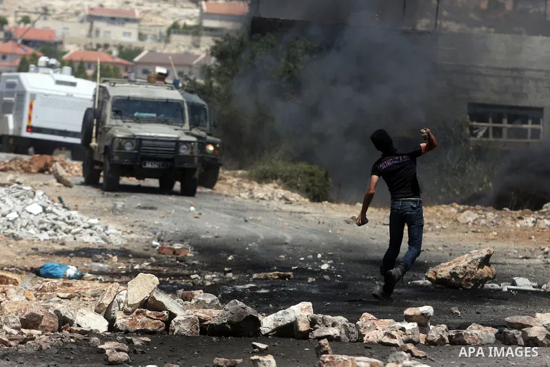 A Palestinian protester throws stones at Israeli truck during clashes following a weekly protest against the nearby Jewish settlement of Kdumim, in the West Bank village of Kufr Qaddum, near Nablus July 13, 2012. Accordi...