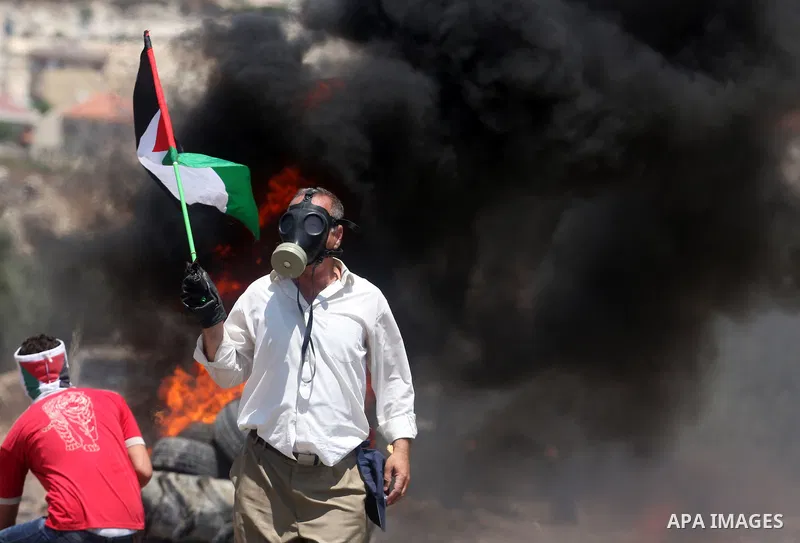 A Palestinian protester holds a national flag during clashes with Israeli security forces following a weekly protest against the nearby Jewish settlement of Kdumim, in the West Bank village of Kufr Qaddum, near Nablus Ju...