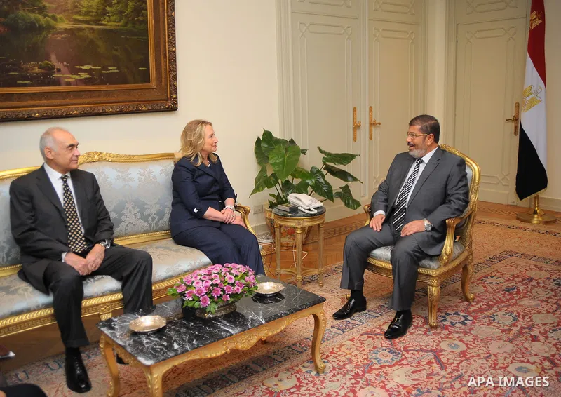 Egyptian Foreign Minister Mohammed Kamel Amr, U. S. Secretary of State Hillary Clinton, and Egyptian President Mohammed Morsi, during a photo opportunity at their meeting at the Presidential palace in Cairo, Egypt, Satur...