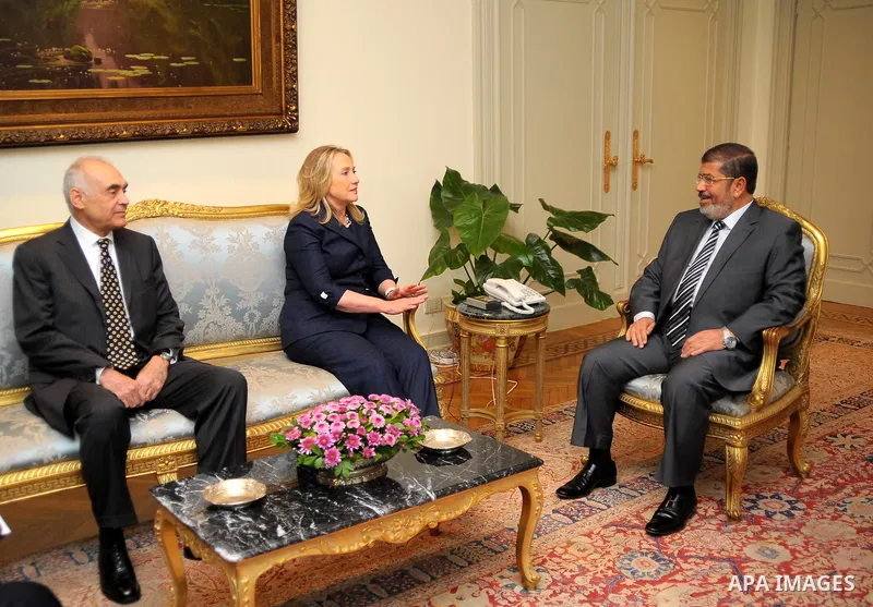 Egyptian Foreign Minister Mohammed Kamel Amr, U. S. Secretary of State Hillary Clinton, and Egyptian President Mohammed Morsi, during a photo opportunity at their meeting at the Presidential palace in Cairo, Egypt, Satur...