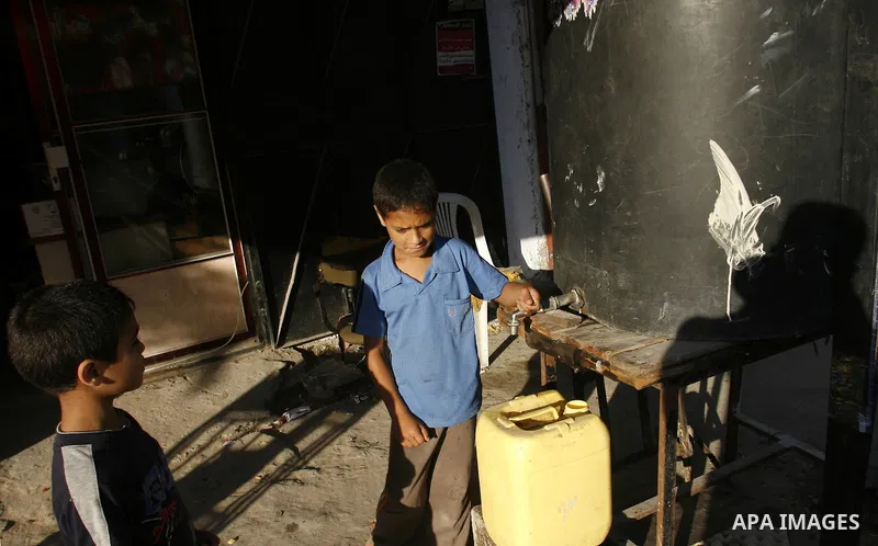 A Palestinian child fills bottles a potable water in the Rafah refugee camp in the southern Gaza Strip on July 14, 2012. Photo by Eyad Al Baba