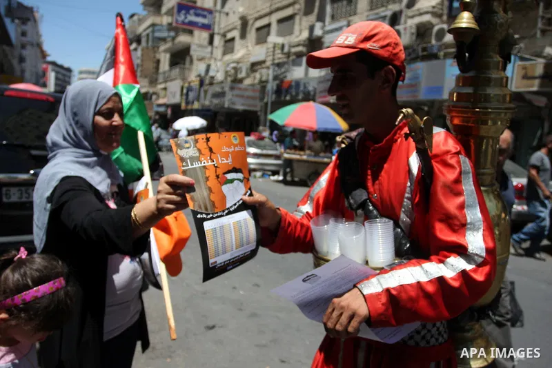 Palestinian protestors hold posters and graphics during a protest demanding Palestinian merchants to boycott Israeli settlement products and goods, and support national economy in the West Bank city of Ramallah ,on July...