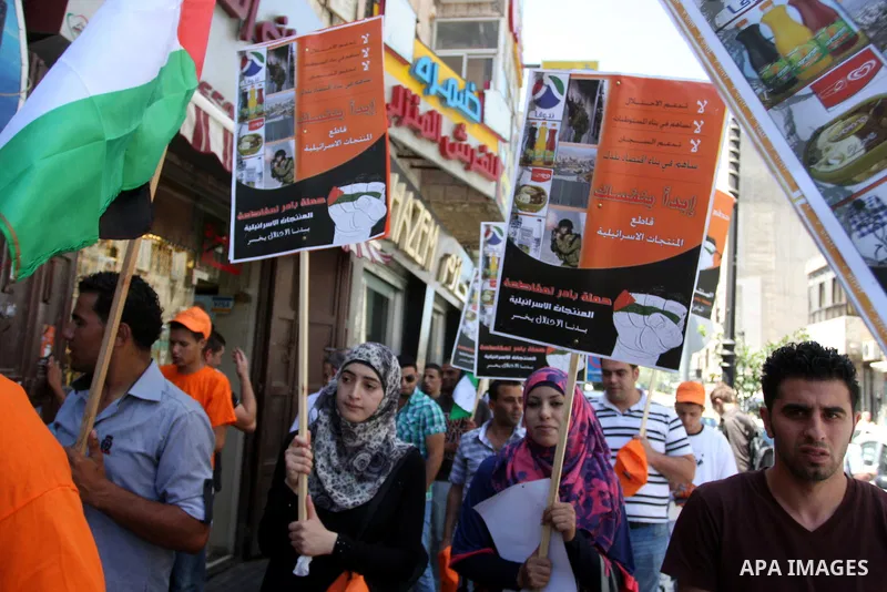Palestinian protestors hold posters and graphics during a protest demanding Palestinian merchants to boycott Israeli settlement products and goods, and support national economy in the West Bank city of Ramallah ,on July...