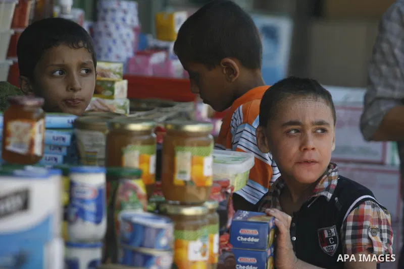 Palestinian children look at a vendor as he displays foodstuff in preparation for the holy month of Ramadan in the Rafah refugee camp in the southern Gaza Strip on July 17, 2012 . Islam's holy month of Ramadan will begin...