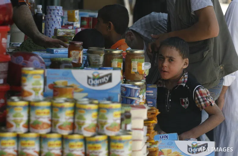 Palestinian children look at a vendor as he displays foodstuff in preparation for the holy month of Ramadan in the Rafah refugee camp in the southern Gaza Strip on July 17, 2012 . Islam's holy month of Ramadan will begin...