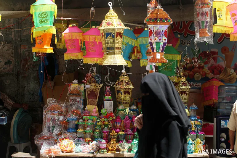 A Palestinian woman walks in front of the shop as the vendor displays goods in preparation for the holy month of Ramadan in the Gaza city on July 17, 2012 . Islam's holy month of Ramadan will begin in few days depending...