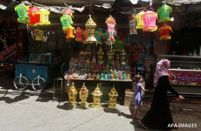 A Palestinian woman walks in front of the shop as the vendor displays goods in preparation for the holy month of Ramadan in the Gaza city on July 17, 2012 . Islam's holy month of Ramadan will begin in few days depending...