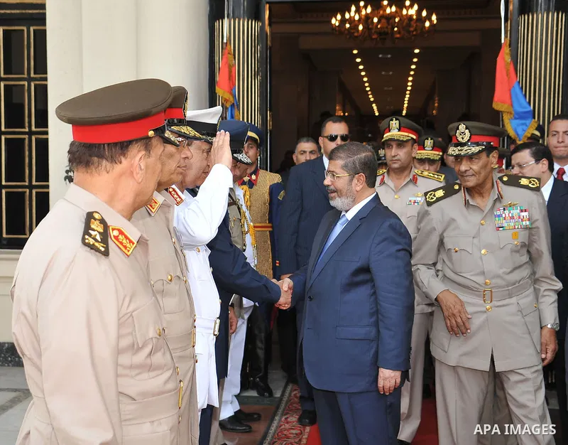 President Mohammed Morsi, center, shakes hands with military officers in Cairo, Egypt, Tuesday, July 17, 2012. Field Marshal Hussein Tantawi is seen at right. Egypt's President Mohammed Morsi hailed the Egyptian army and...