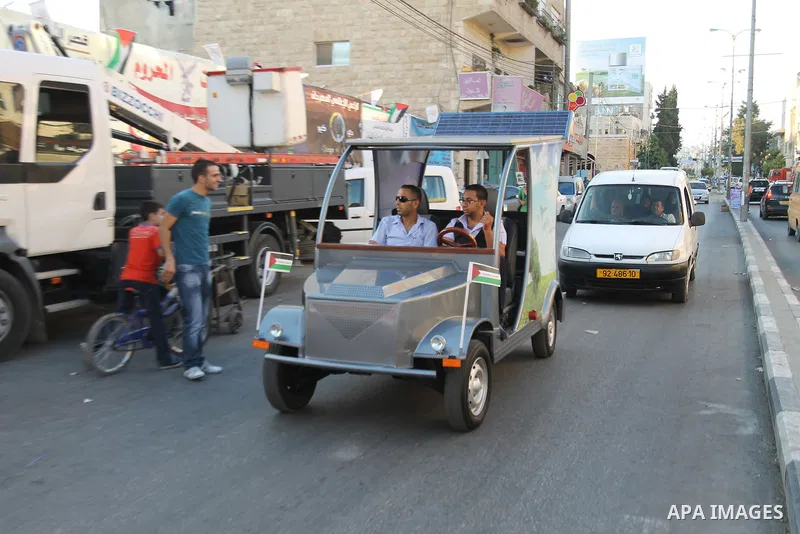Palestinians inspect the first Palestinian electric car during an international environment expo held in the West Bank city of Hebron, on 17 July 2012. The exhibitors attended the expo bringing such new technologies and...