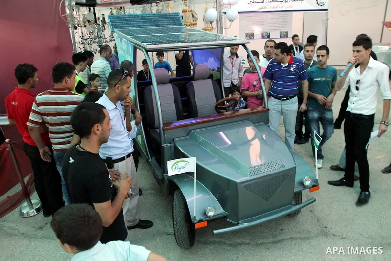 Palestinians inspect the first Palestinian electric car during an international environment expo held in the West Bank city of Hebron, on 17 July 2012. The exhibitors attended the expo bringing such new technologies and...
