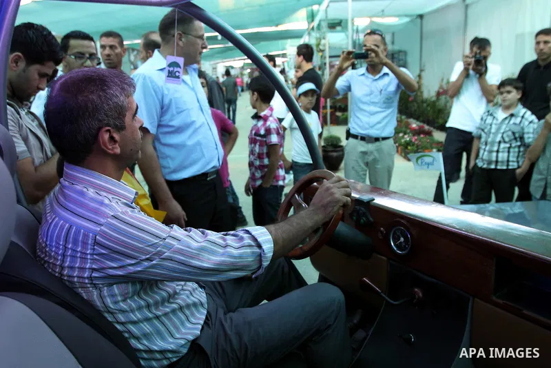 Palestinians inspect the first Palestinian electric car during an international environment expo held in the West Bank city of Hebron, on 17 July 2012. The exhibitors attended the expo bringing such new technologies and...