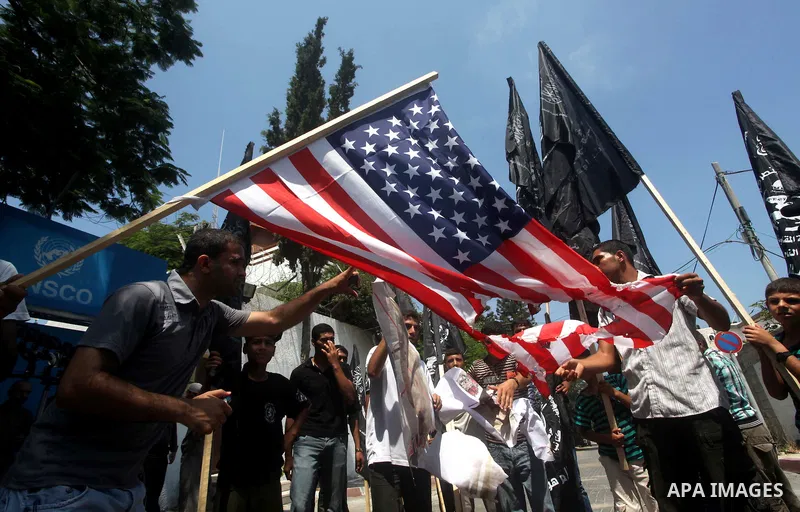 Palestinian supporters of the Popular Resistance Movement linked Hamas, burn a U.S. flag and hold a poster of Myanmar's President Thein Sein reading in Arabic "President of Burma despicable," during a demonstration calli...