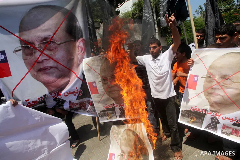 Palestinian supporters of the Popular Resistance Movement linked Hamas, burn a U.S. flag and hold a poster of Myanmar's President Thein Sein reading in Arabic "President of Burma despicable," during a demonstration calli...