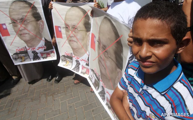 Palestinian supporters of the Popular Resistance Movement linked Hamas, burn a U.S. flag and hold a poster of Myanmar's President Thein Sein reading in Arabic "President of Burma despicable," during a demonstration calli...