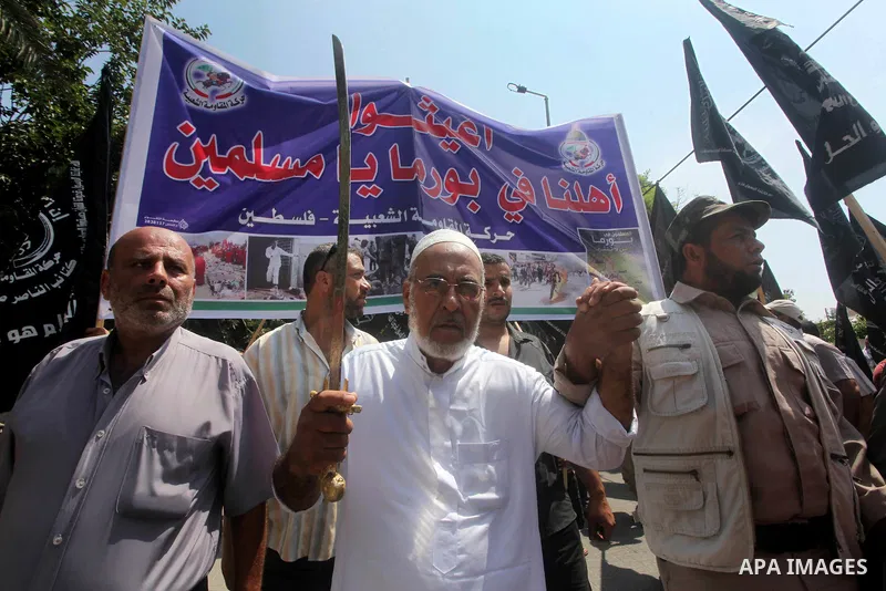 A Palestinian supporter of the Popular Resistance Movement linked Hamas, holds a sword as others carry posters of Myanmar's President Thein Sein during a demonstration calling to stop killing the Burmese Muslims in Myanm...