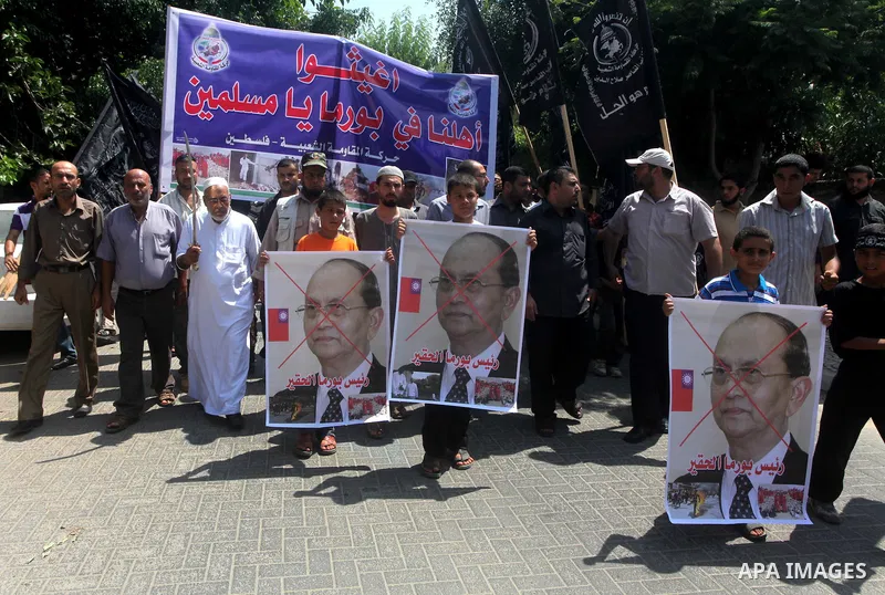 A Palestinian supporter of the Popular Resistance Movement linked Hamas, holds a sword as others carry posters of Myanmar's President Thein Sein during a demonstration calling to stop killing the Burmese Muslims in Myanm...