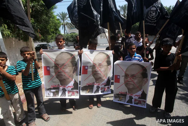 A Palestinian supporter of the Popular Resistance Movement linked Hamas, holds a sword as others carry posters of Myanmar's President Thein Sein during a demonstration calling to stop killing the Burmese Muslims in Myanm...
