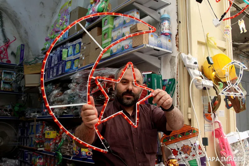 A Palestinian vendor decorates his shop with an electric crescent in preparation for the holy month of Ramadan in the West Bank city of Nablus, on July 18, 2012 . Islam's holy month of Ramadan will begin in few days depe...
