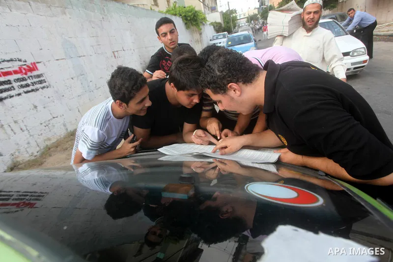 Palestinian secondary school students read a local newspaper to find their results in Gaza city on July 19, 2012. The Ministry of Education in Gaza Strip and the West Bank announced the results together. Photo by Ashraf...