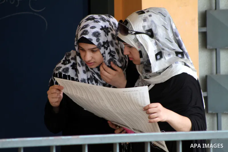 Palestinian secondary school students read a local newspaper to find their results in Gaza city on July 19, 2012. The Ministry of Education in Gaza Strip and the West Bank announced the results together. Photo by Ashraf...
