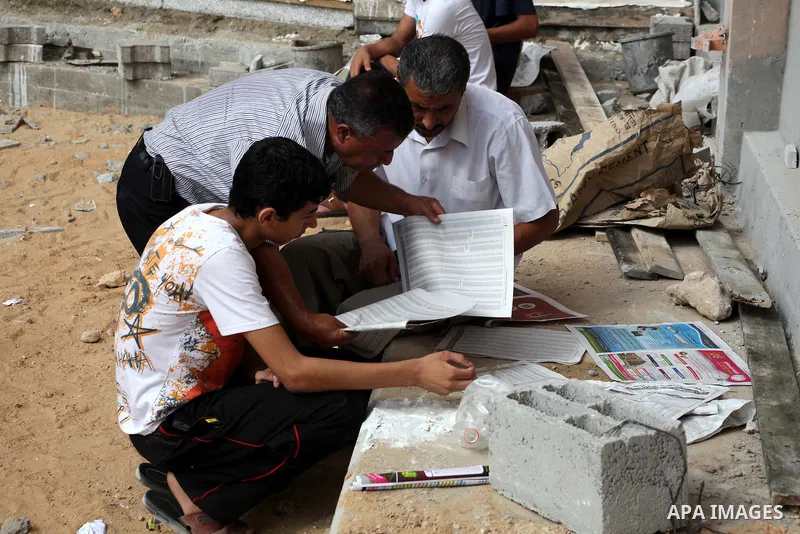 Palestinian secondary school students read a local newspaper to find their results in Gaza city on July 19, 2012. The Ministry of Education in Gaza Strip and the West Bank announced the results together. Photo by Ashraf...