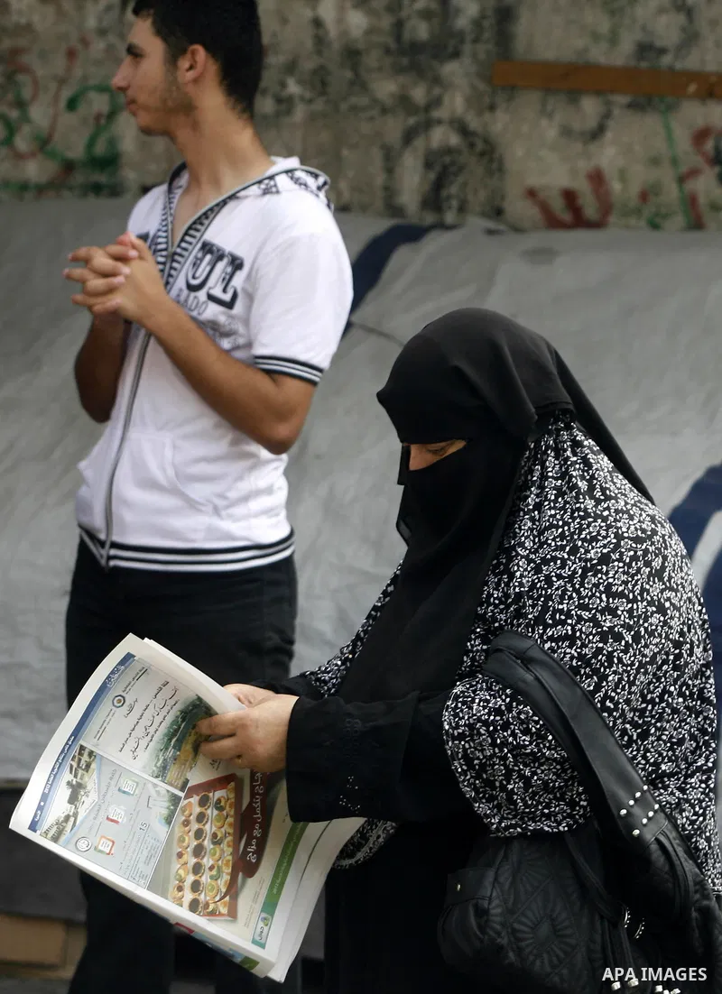 Palestinian relatives students read a local newspaper to find their results in Rafah in the southern Gaza Strip on July 19, 2012. The Ministry of Education in Gaza Strip and the West Bank announced the results together....