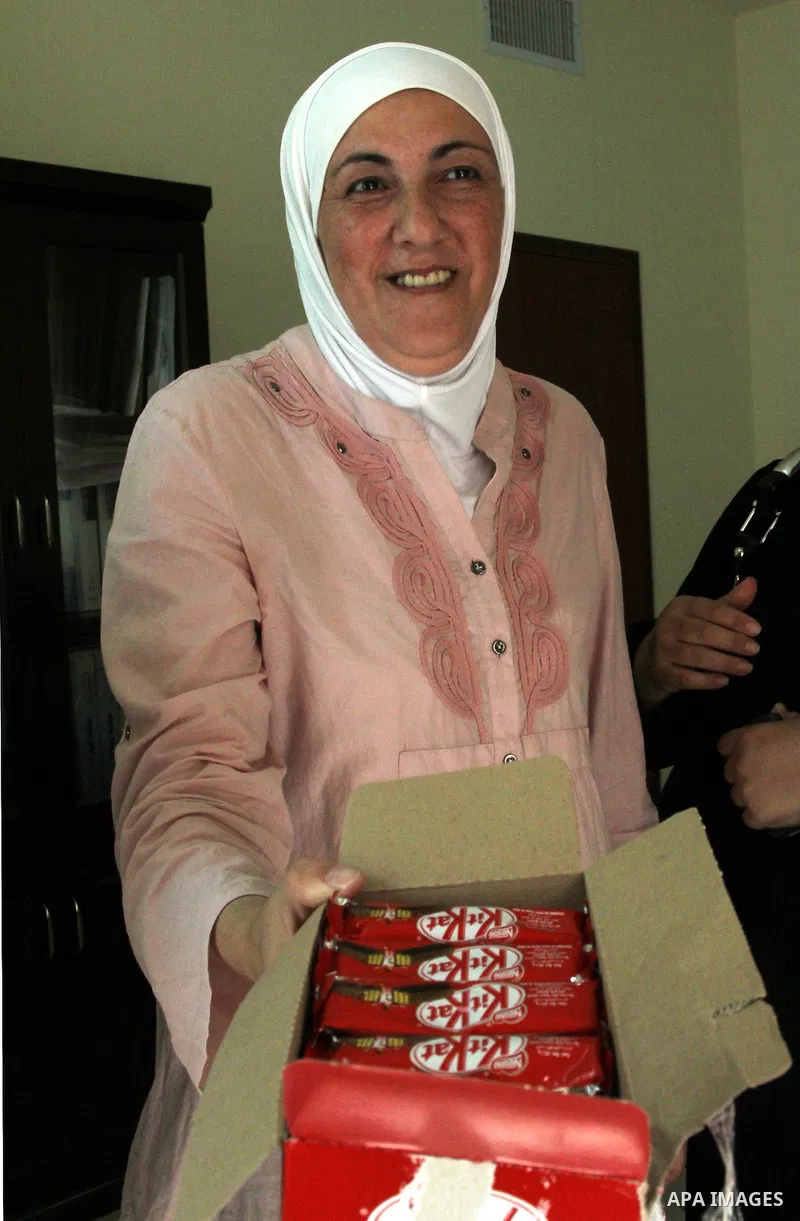 A Palestinian woman gives candy after heard the results of final exams of her high school daughter known as "Tawjihi" in the West Bank city of Nablus, on July 19, 2012. The Ministry of Education in Gaza Strip announced t...