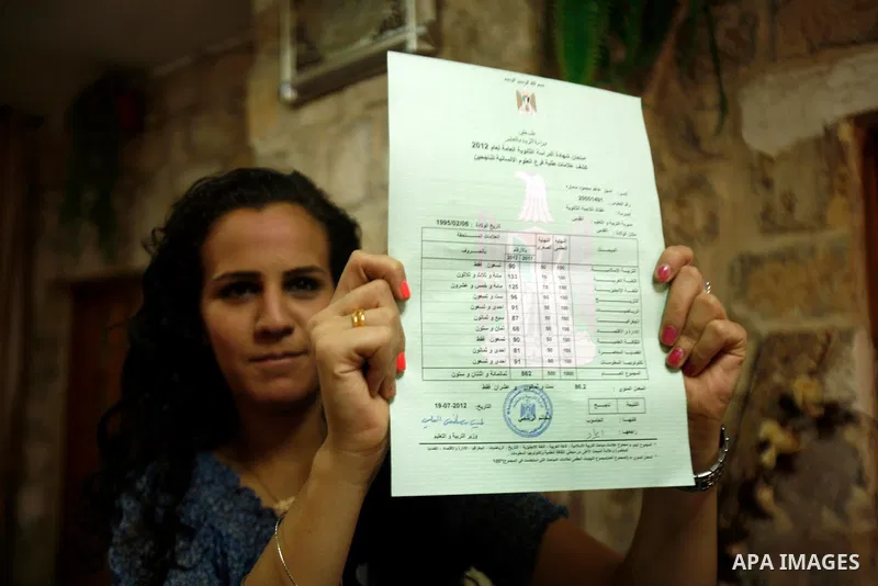 A Palestinian high school student shows the results of her final exams known as "Tawjihi" in Jerusalem, on July 19, 2012. The Ministry of Education in Gaza Strip announced the final results coincide with the West Bank. P...