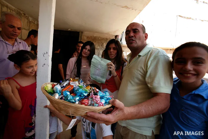A Palestinian man gives candy after heard the results of final exams of his high school daughter known as "Tawjihi" in Jerusalem, on July 19, 2012. The Ministry of Education in Gaza Strip announced the final results coin...