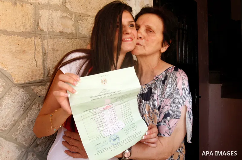 A Palestinian high school student shows the results of her final exams known as "Tawjihi" in Jerusalem, on July 19, 2012. The Ministry of Education in Gaza Strip announced the final results coincide with the West Bank. P...