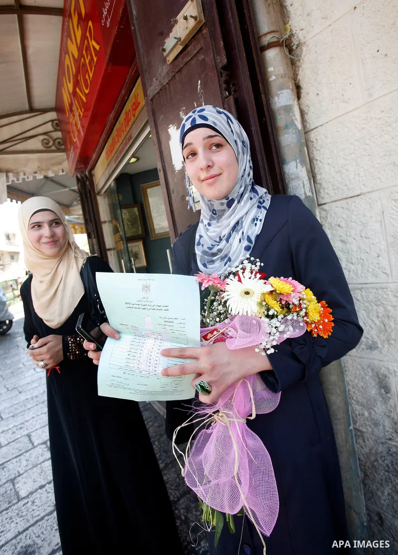 A Palestinian high school student shows the results of her final exams known as "Tawjihi" in Jerusalem, on July 19, 2012. The Ministry of Education in Gaza Strip announced the final results coincide with the West Bank. P...