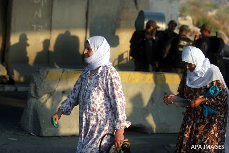 An Israeli border police officer checks documents of Palestinian women who wait to cross the Qalandia checkpoint on the outskirts of the West Bank city of Ramallah on July 20, 2012 as they head to the Al-Aqsa mosque comp...