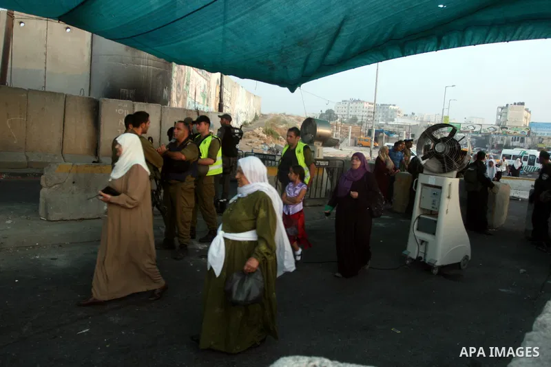 An Israeli border police officer checks documents of Palestinian women who wait to cross the Qalandia checkpoint on the outskirts of the West Bank city of Ramallah on July 20, 2012 as they head to the Al-Aqsa mosque comp...