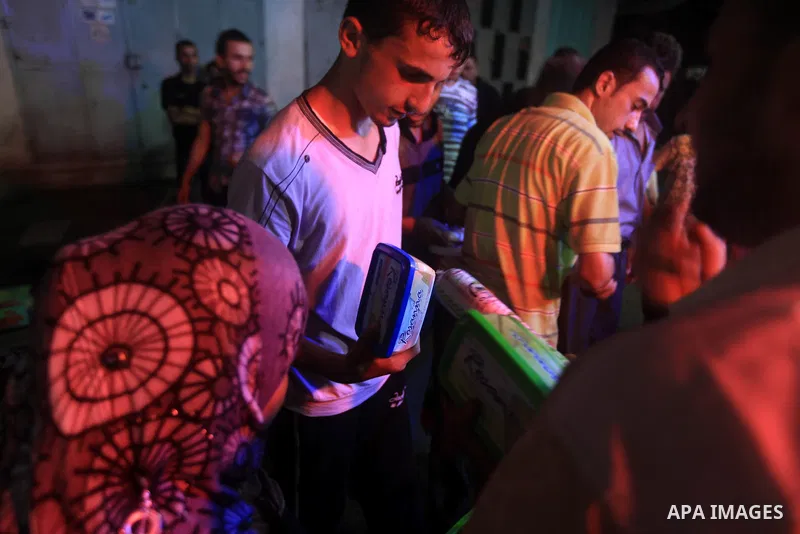 Palestinians Inspect goods as the vendor displays it in preparation for the holy month of Ramadan in the Gaza city on July 19, 2012 .Ramadan is the ninth month of the Islamic calender, a month of fasting, in which partic...