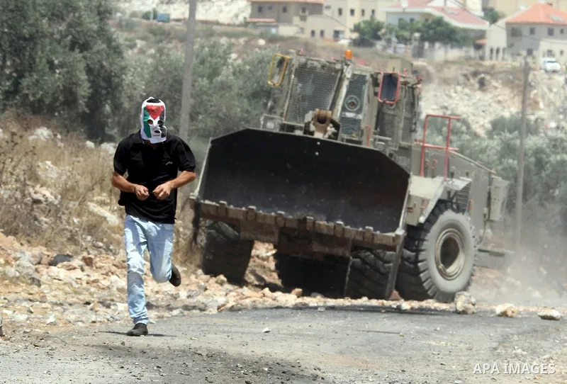 A Palestinian protestor throws stones at Israeli truck during clashes as they protest against the Jewish settlement of Kdumim, near Nablus, West Bank, 20 July 2012. According to medical sources 16 Palestinians were injur...