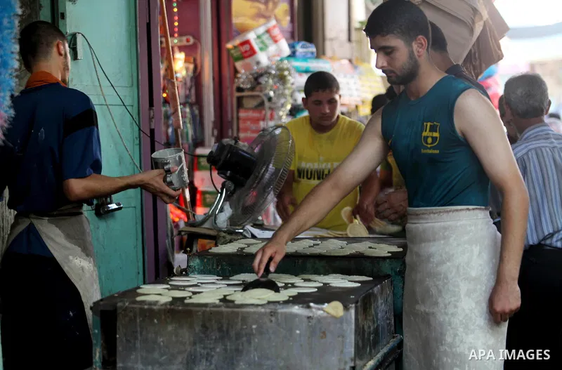 A Palestinian vendor prepares a traditional pancake known as "Qatayef" on the second day of the holy month of Ramadan, at a shop in Gaza City, on 21 July 2012. Muslims around the world abstain from eating, drinking and c...