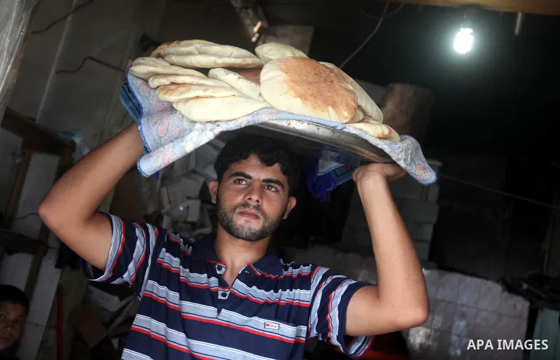 A Palestinian man carries loaves of bread baked in a traditional mud oven during Ramadan in Jabalya refugee camp, northen Gaza Strip on July 23, 2012. Muslims around the world abstain from eating, drinking and conducting...