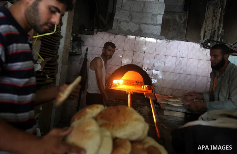 A Palestinian man bakes loaves of bread in his traditional mud oven during Ramadan in Jabalya refugee camp, northen Gaza Strip on July 23, 2012. Muslims around the world abstain from eating, drinking and conducting sexua...