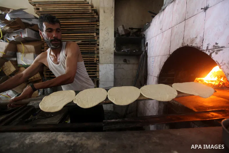 A Palestinian man bakes loaves of bread in his traditional mud oven during Ramadan in Jabalya refugee camp, northen Gaza Strip on July 23, 2012. Muslims around the world abstain from eating, drinking and conducting sexua...
