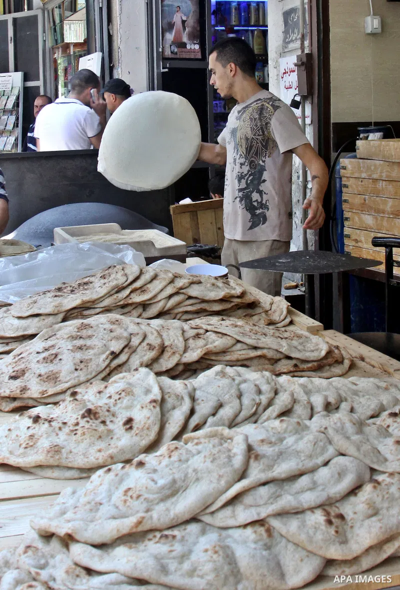A Palestinian man bakes loaves of bread in his traditional mud oven during Ramadan in the West Bank city of Nablus on July 25, 2012. Muslims around the world abstain from eating, drinking and conducting sexual relations...
